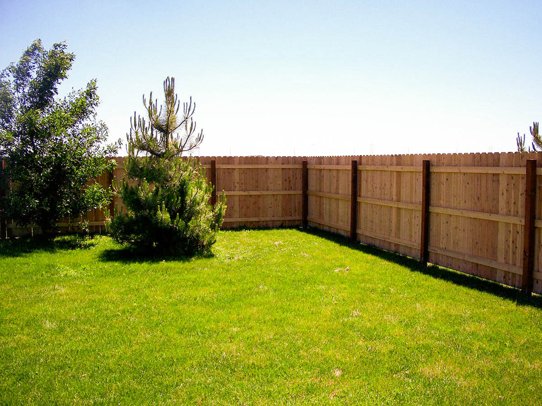 A cedar privacy fence running along a residential property line in the Tulsa metro